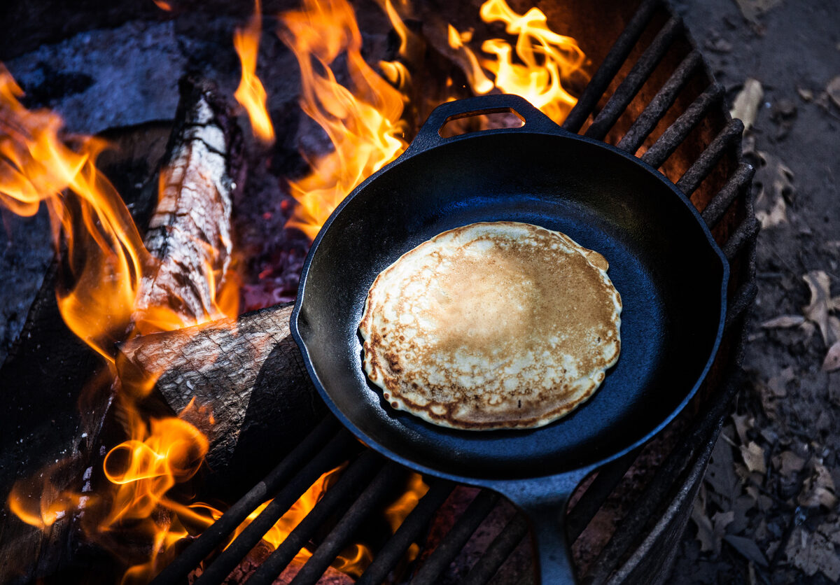 Cooking a pancake over a campfire.