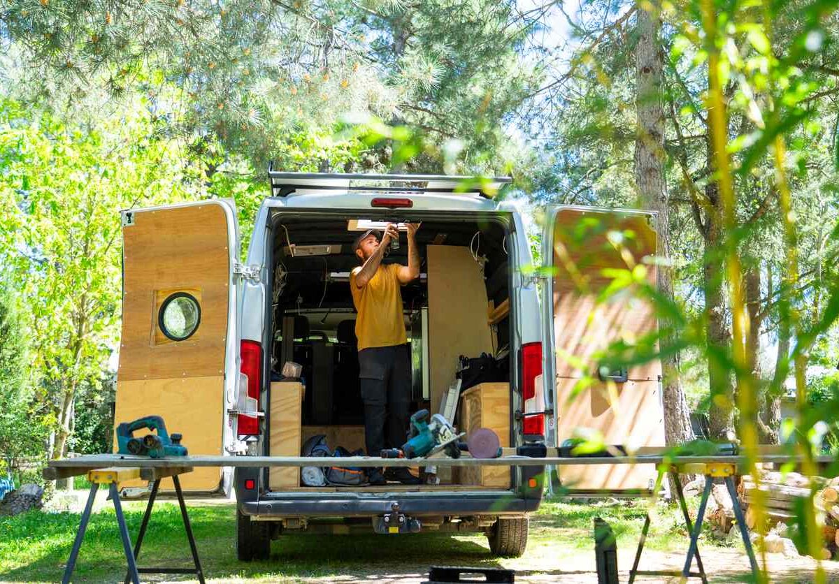 A man installs lighting to his camper to prepare for van life.
